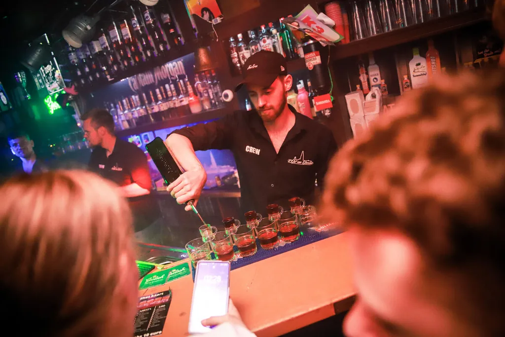 Barman schenkt een rij shotjes in achter de bar