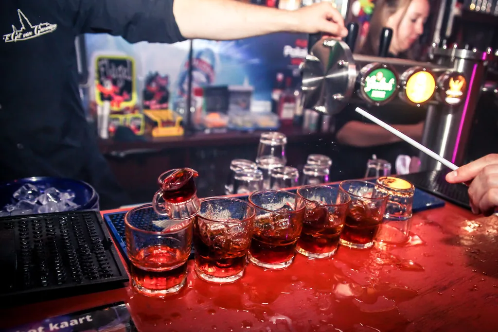 Rij shotglazen die op de bar wordt volgeschonken