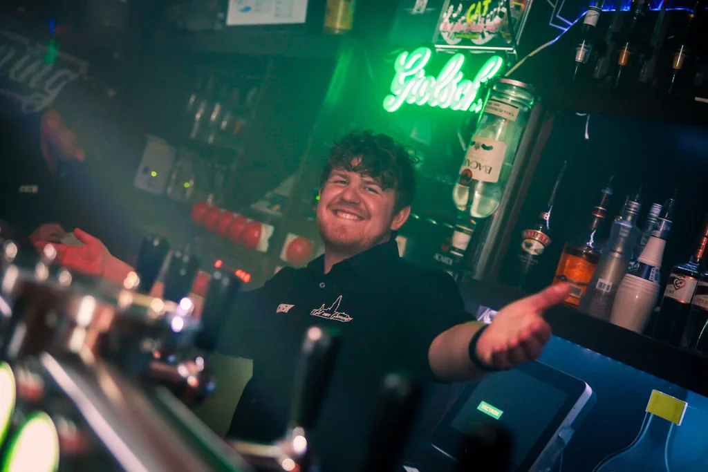Barman achter de tap onder het groene neonlicht
